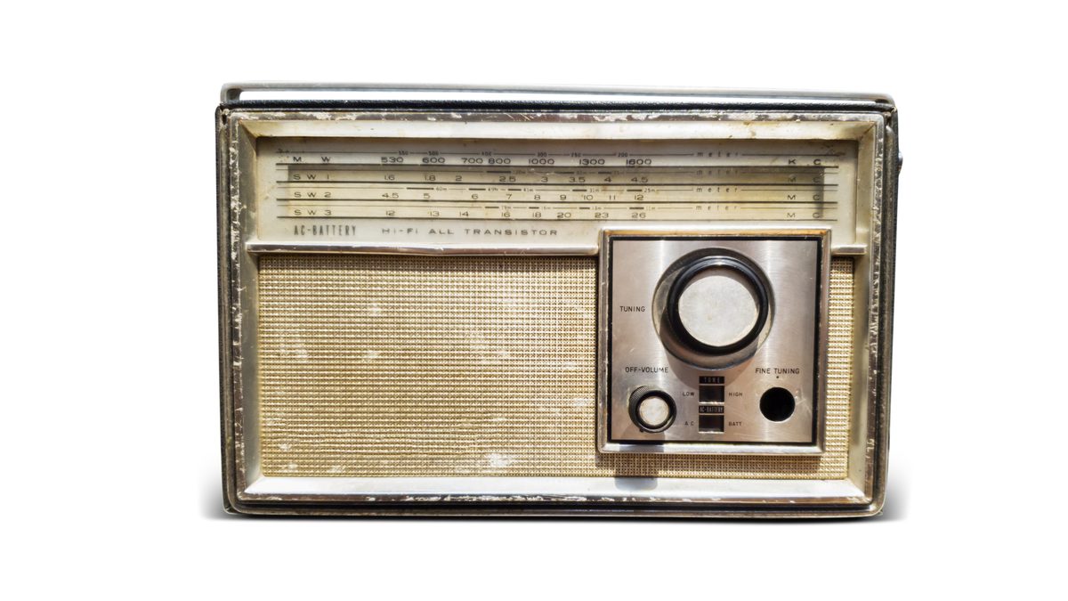 A worn old transistor radio with a fabric grille, a tuning dial and medium and short wave bands