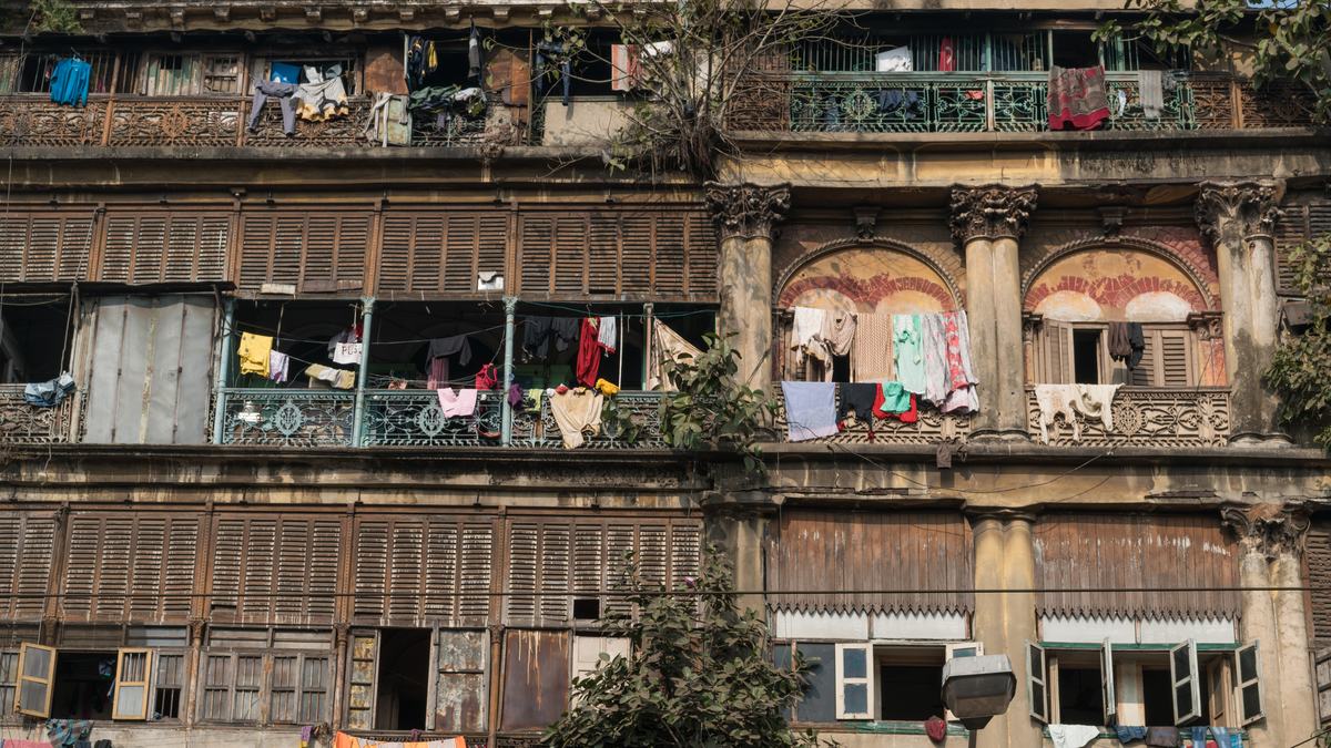 The front of an old Kolkata house: wooden louvred shutters, cast-iron balconies, Corinthian columns and washing on the balconies