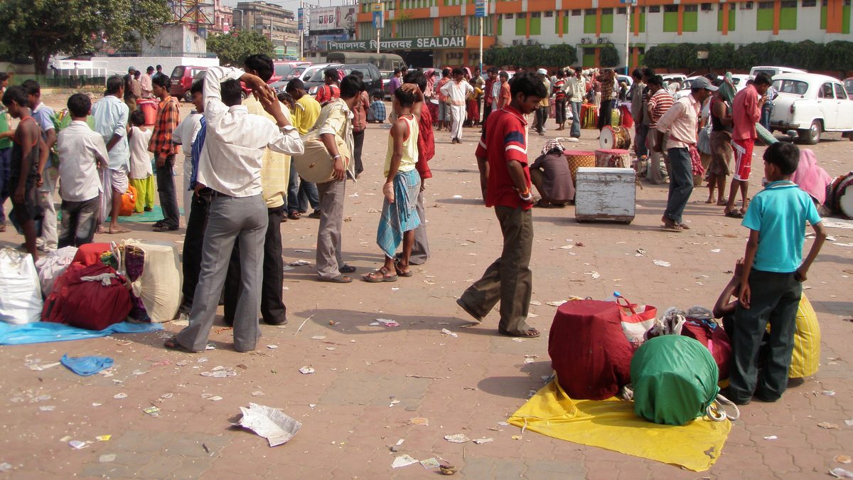 Dhakis with their drums wrapped in red, green and yellow cloth on the forecourt outside Sealdah station, Kolkata, the station building and its sign behind them